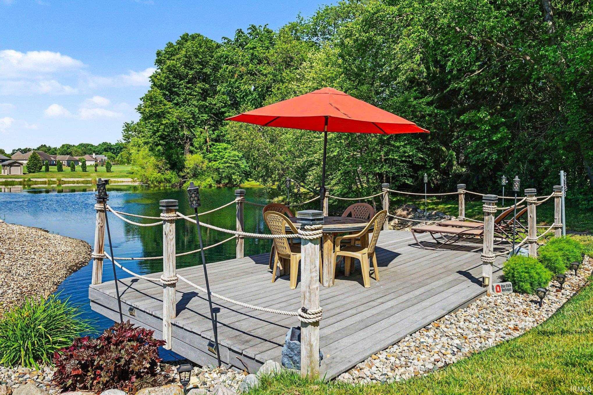 Lakefront dock featuring composite decking, rope railings with decorative posts, and integrated landscaping with stone accents