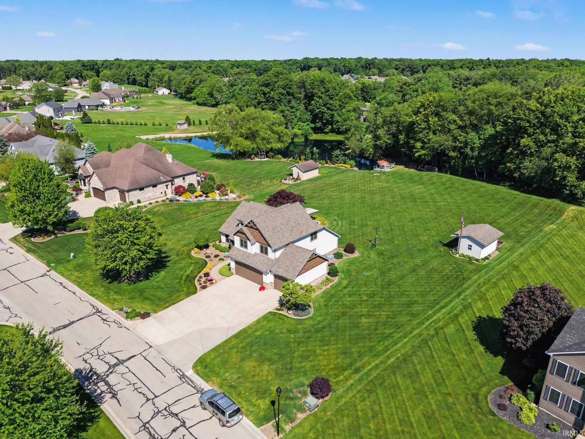 Expansive property featuring a two-story residence with a gabled roof, attached garage, and a concrete driveway