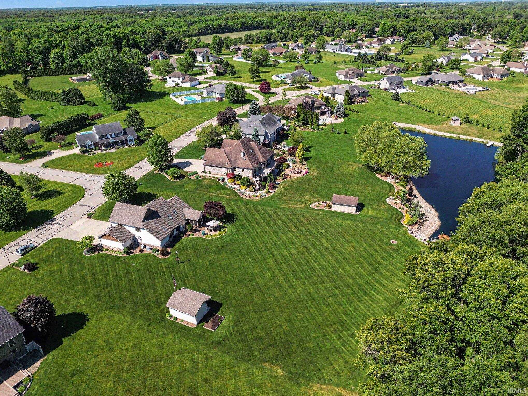 Expansive property featuring a meticulously maintained lawn, a serene private pond, and mature trees