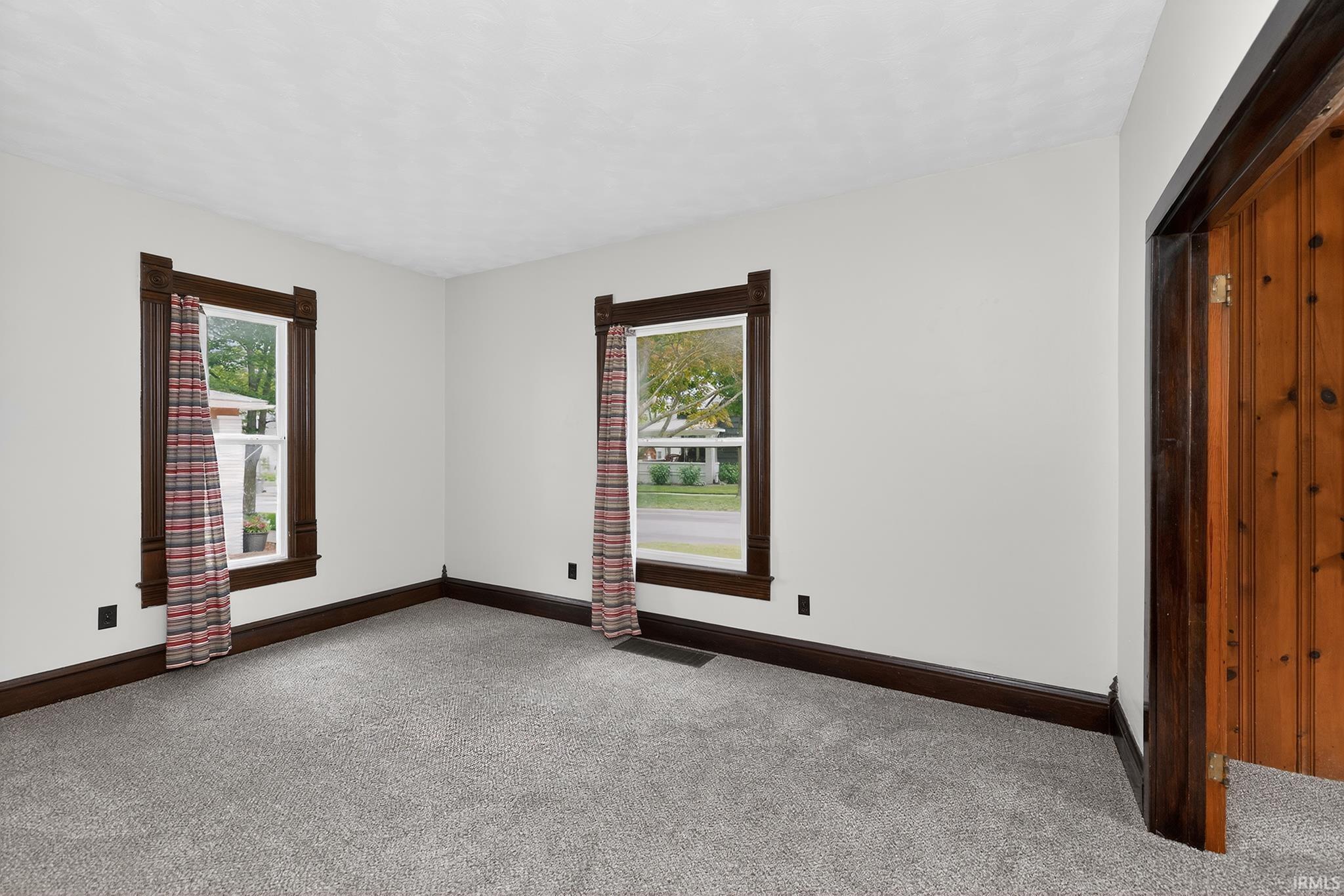 Room featuring light gray walls, dark wood trim, and gray carpeting