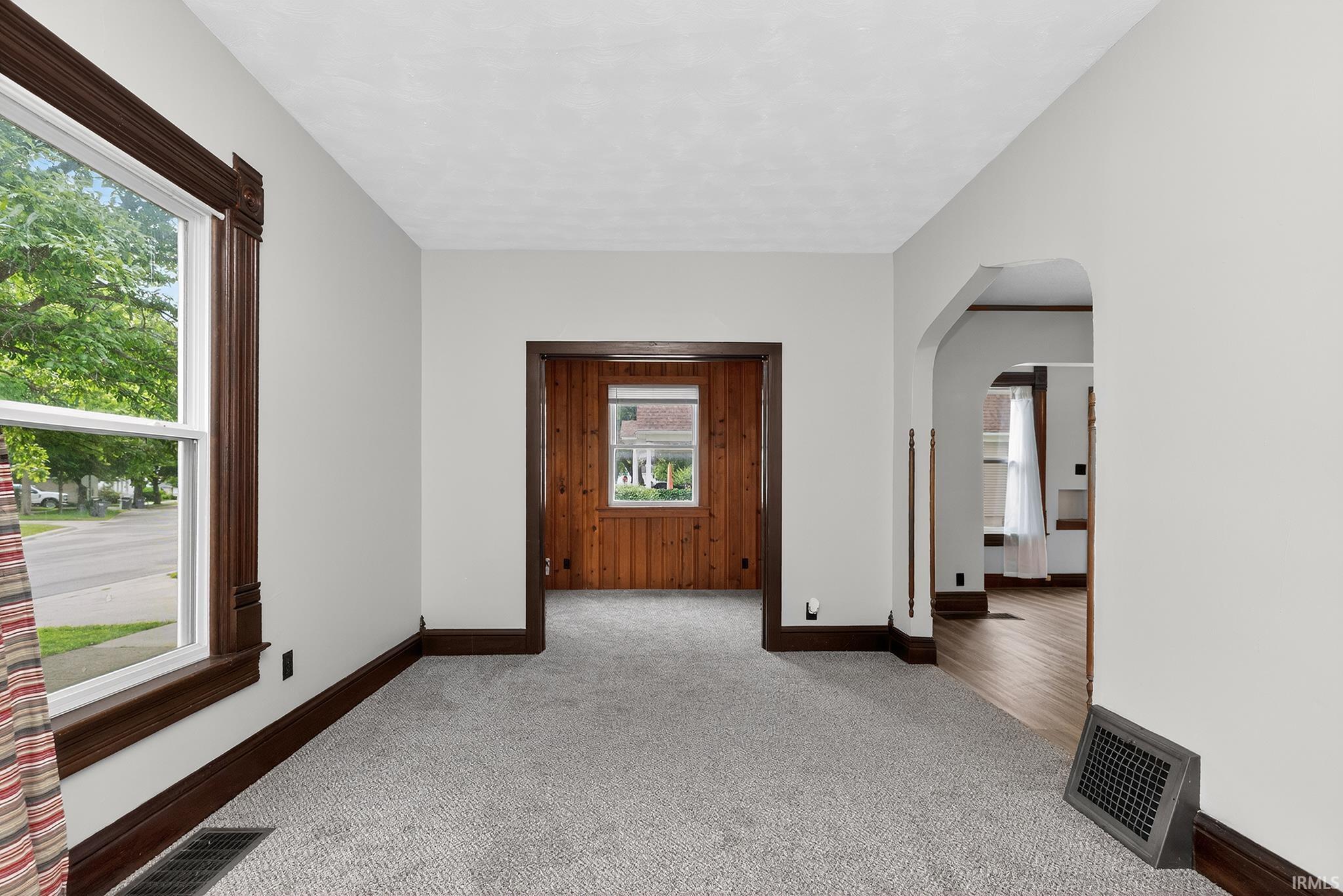 Interior room featuring light gray wall paint, dark wood trim, and light gray carpet flooring