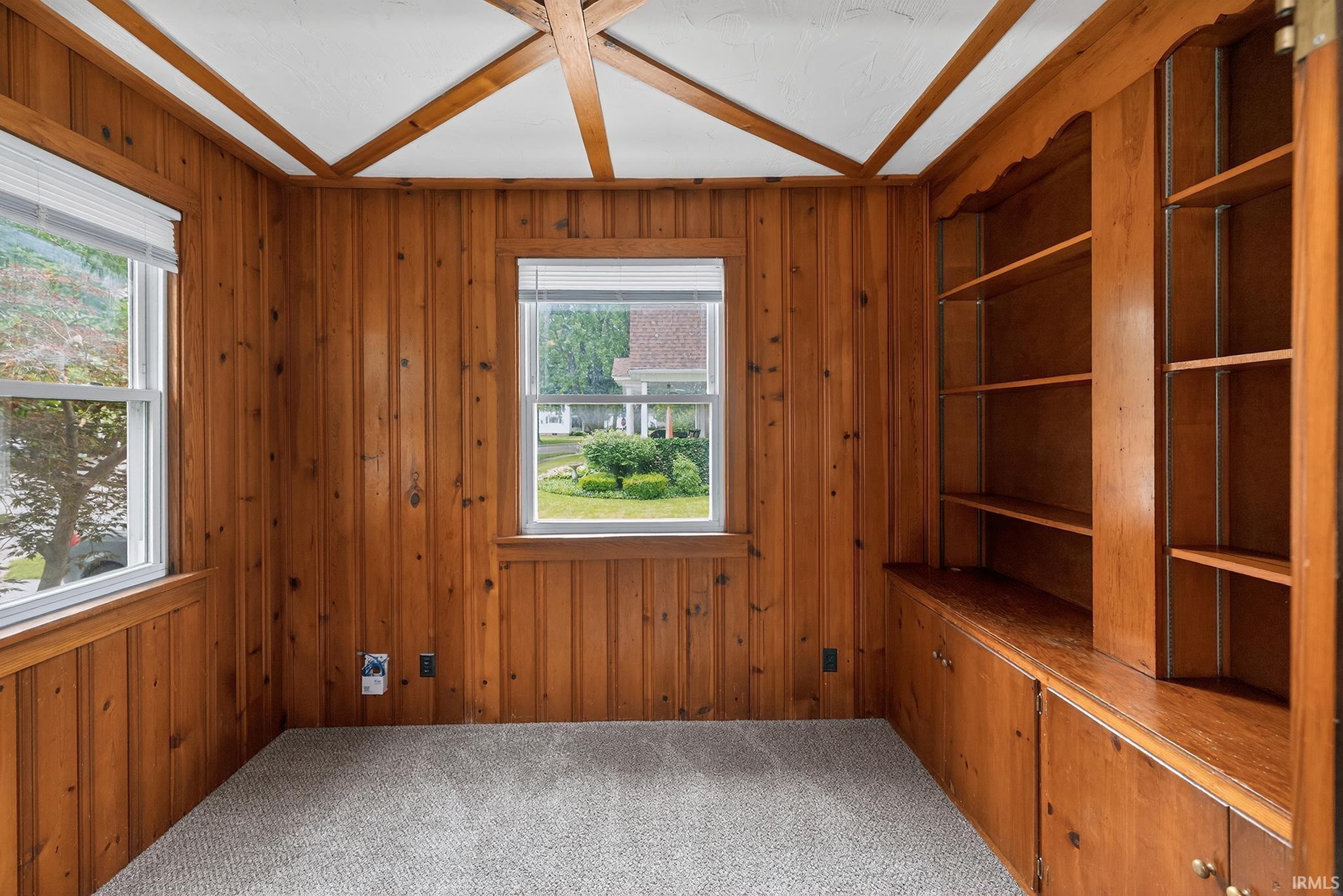 Wood-paneled room featuring a coffered ceiling with white panels and wood-finish beams