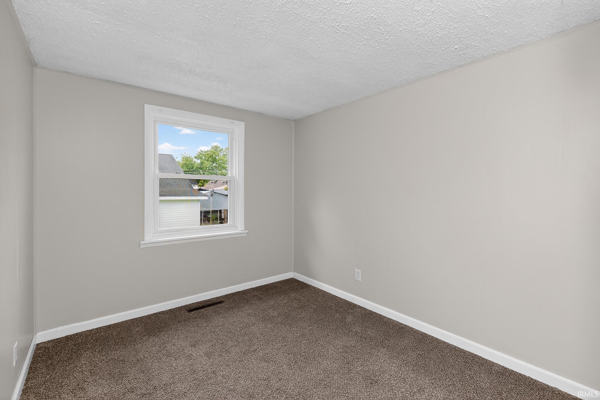 Neutral gray walls with white trim, a single window, and brown carpeting