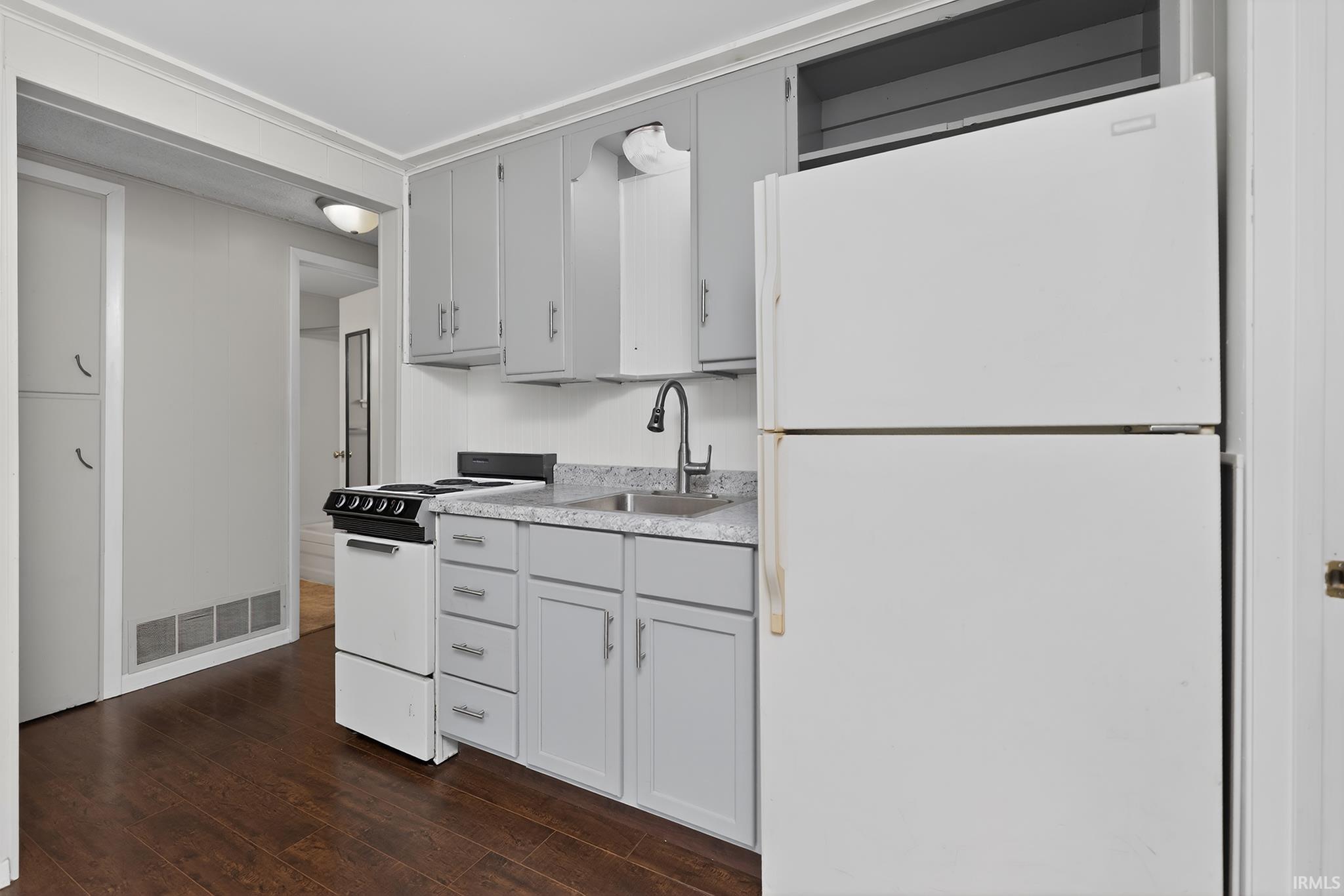Kitchen featuring wood-finish flooring, white appliances, gray cabinetry, and light-colored countertops