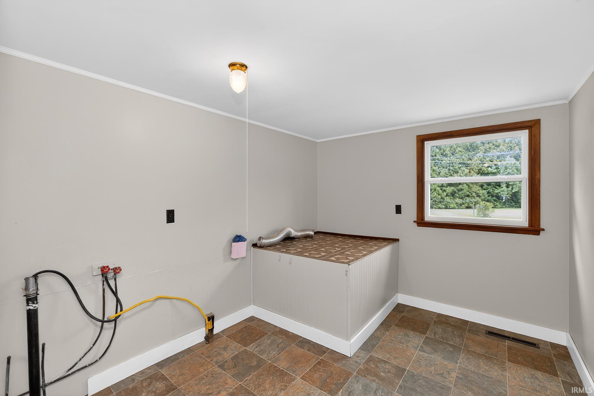 Room featuring light gray walls, white trim, and a window with wood framing