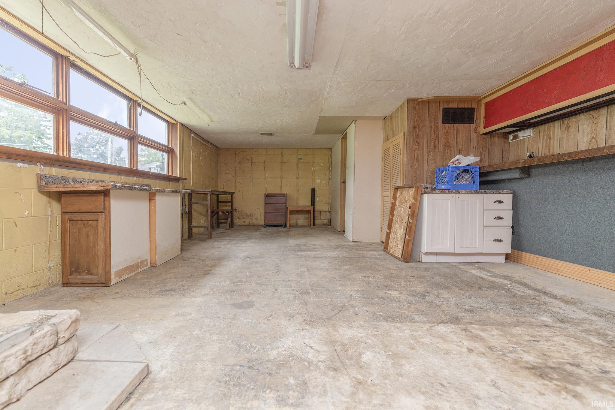 Spacious interior area featuring concrete flooring and a row of large windows providing ample natural light