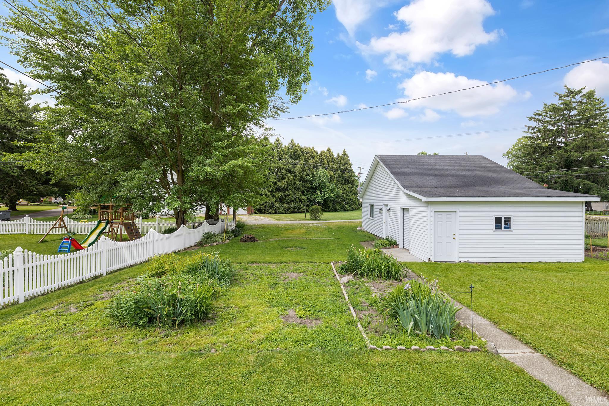 Detached garage structure with white siding and a dark shingle roof