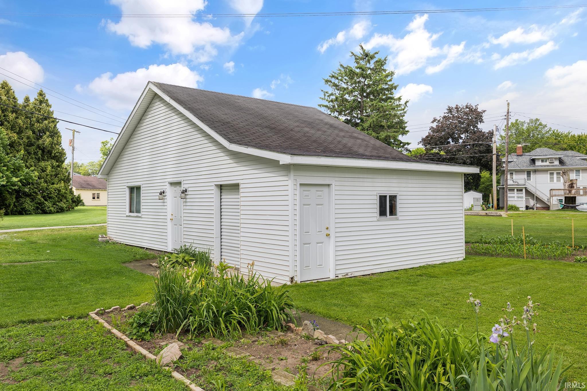 Detached auxiliary building with white horizontal siding and a dark shingle roof