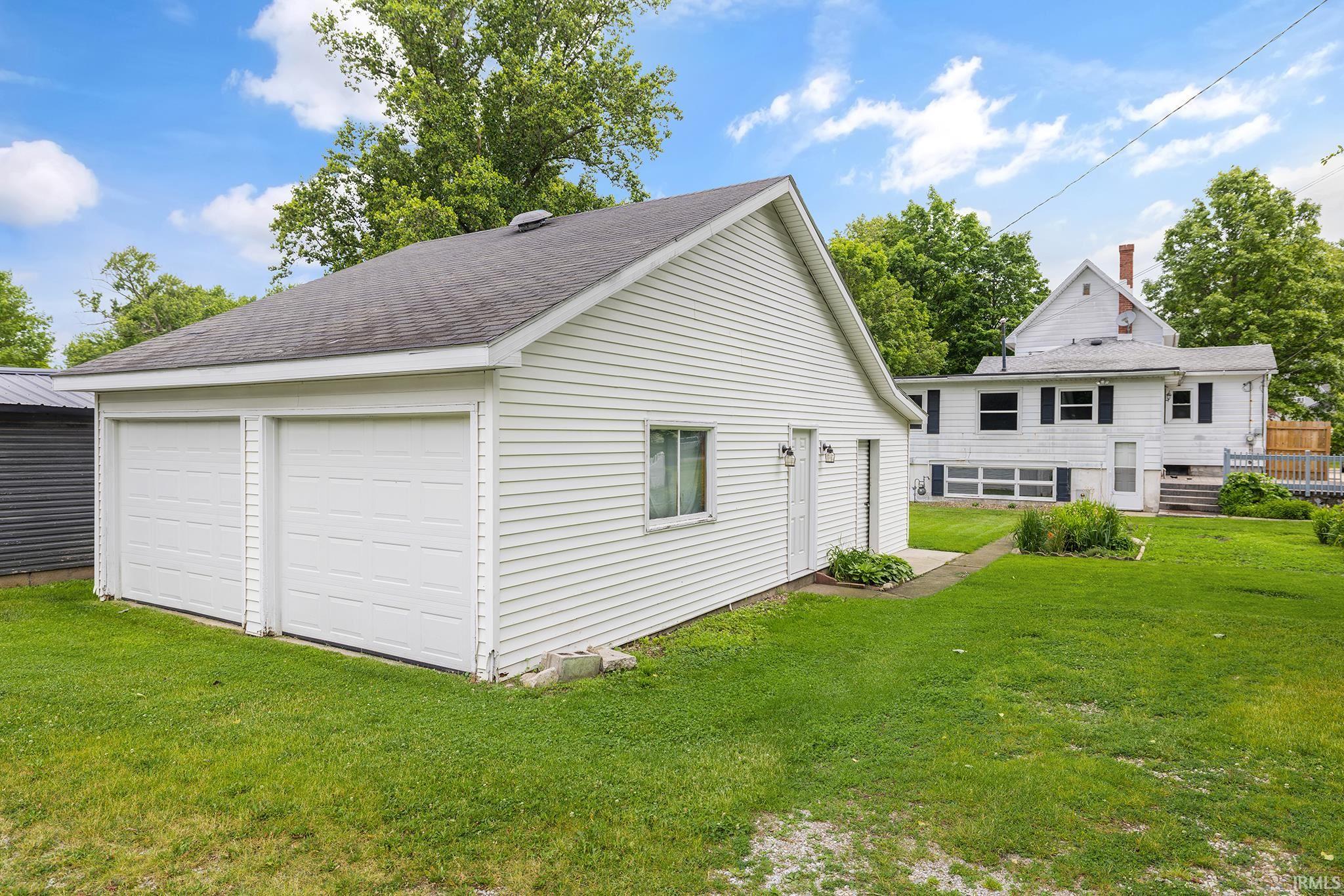 Detached two-car garage with white paneled garage doors, white siding, and an asphalt shingle roof