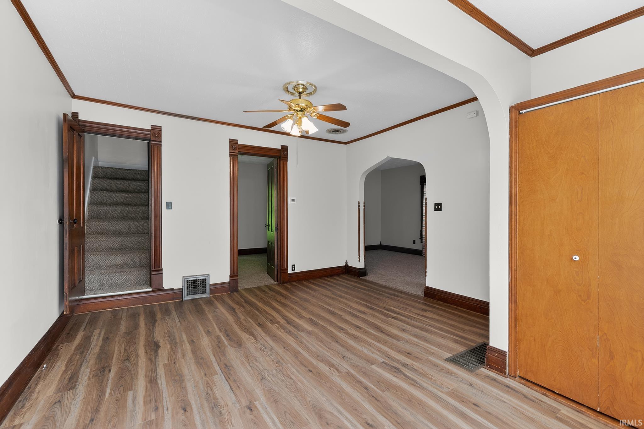 Expansive room featuring wood-finish flooring, white walls, and dark wood trim
