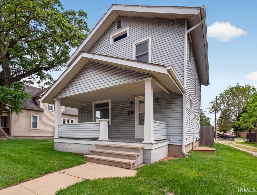 Two-story residence featuring light gray siding, a covered front porch, and a gable roofline