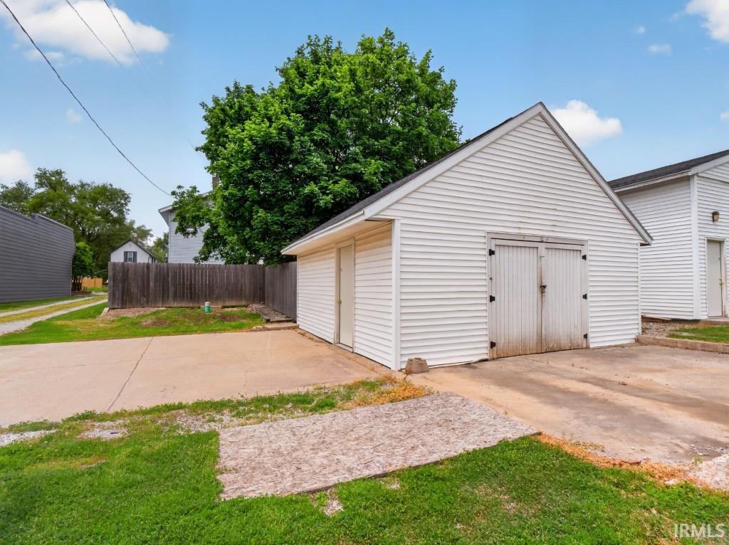 Detached garage structure featuring white horizontal siding and a gable roofline