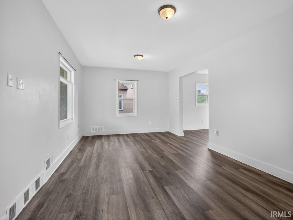 Spacious room featuring wood-finish flooring, light gray walls, white trim, and two recessed windows