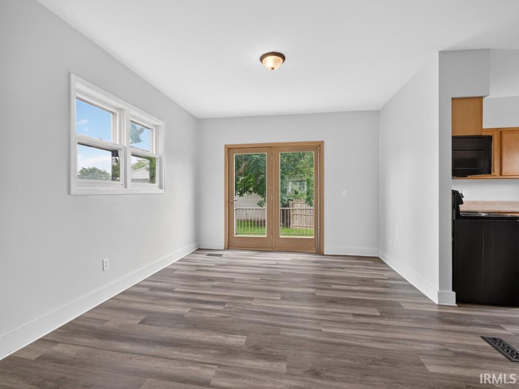 Spacious room featuring wood-finish flooring, white baseboards, and light gray walls