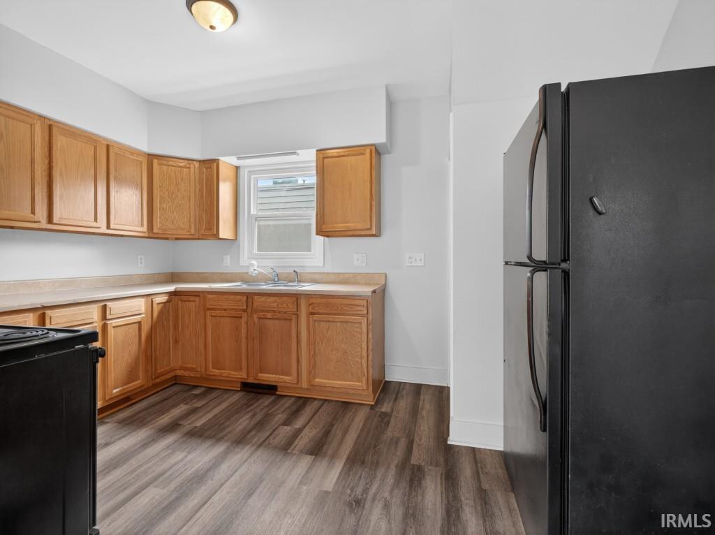 Kitchen featuring wood-finish flooring, natural wood cabinetry, light-toned countertops, and a window above the sink