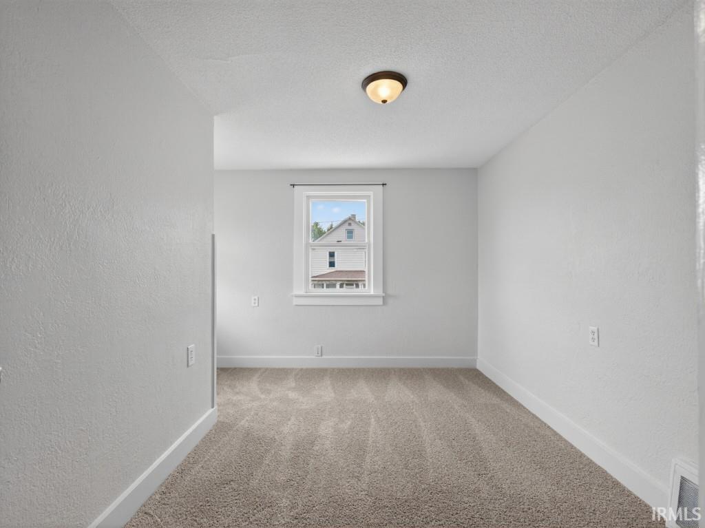 Carpeted room featuring a single window with white trim, a semi-flush mount ceiling light, and white baseboards
