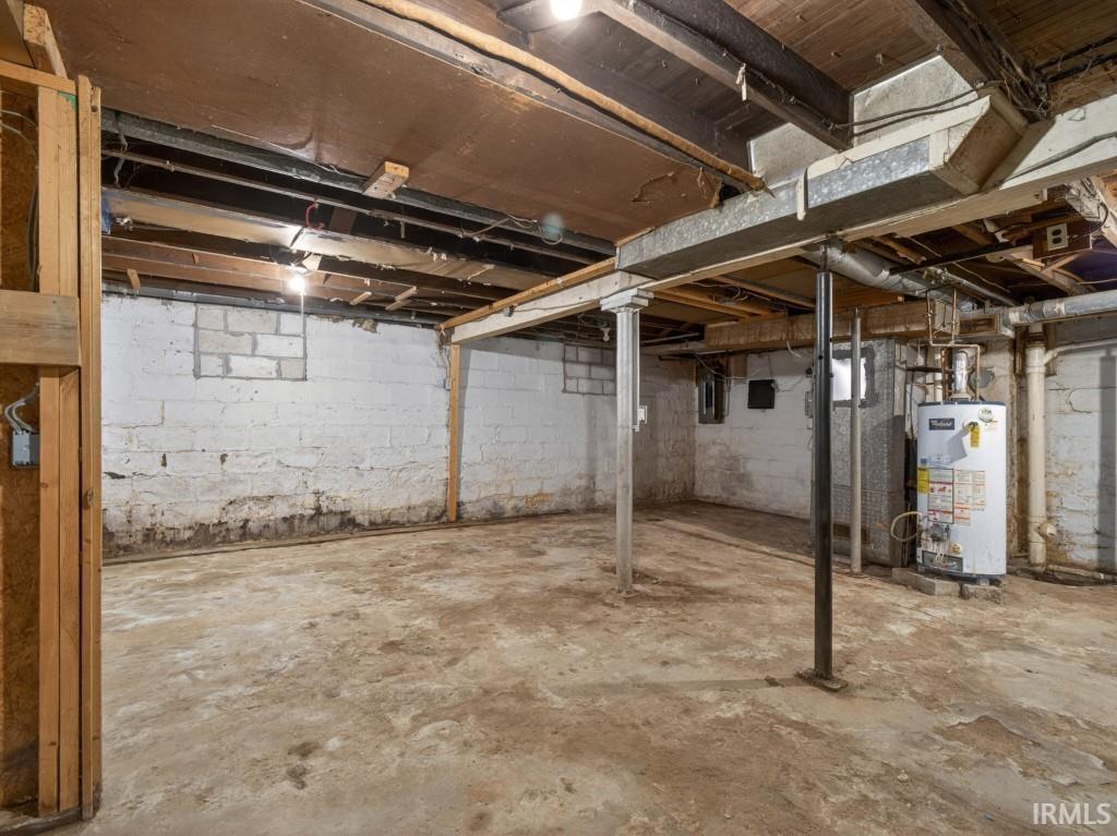 Unfinished basement offering ample storage space with exposed ceiling joists and a concrete floor