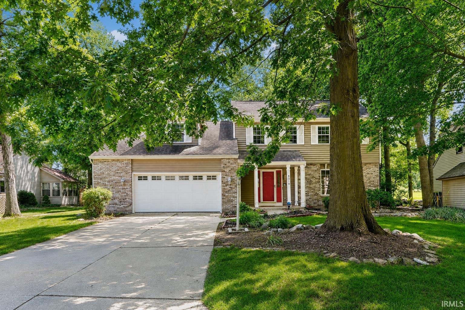 Two-story residence featuring a stone and siding exterior, an attached two-car garage, and a concrete driveway