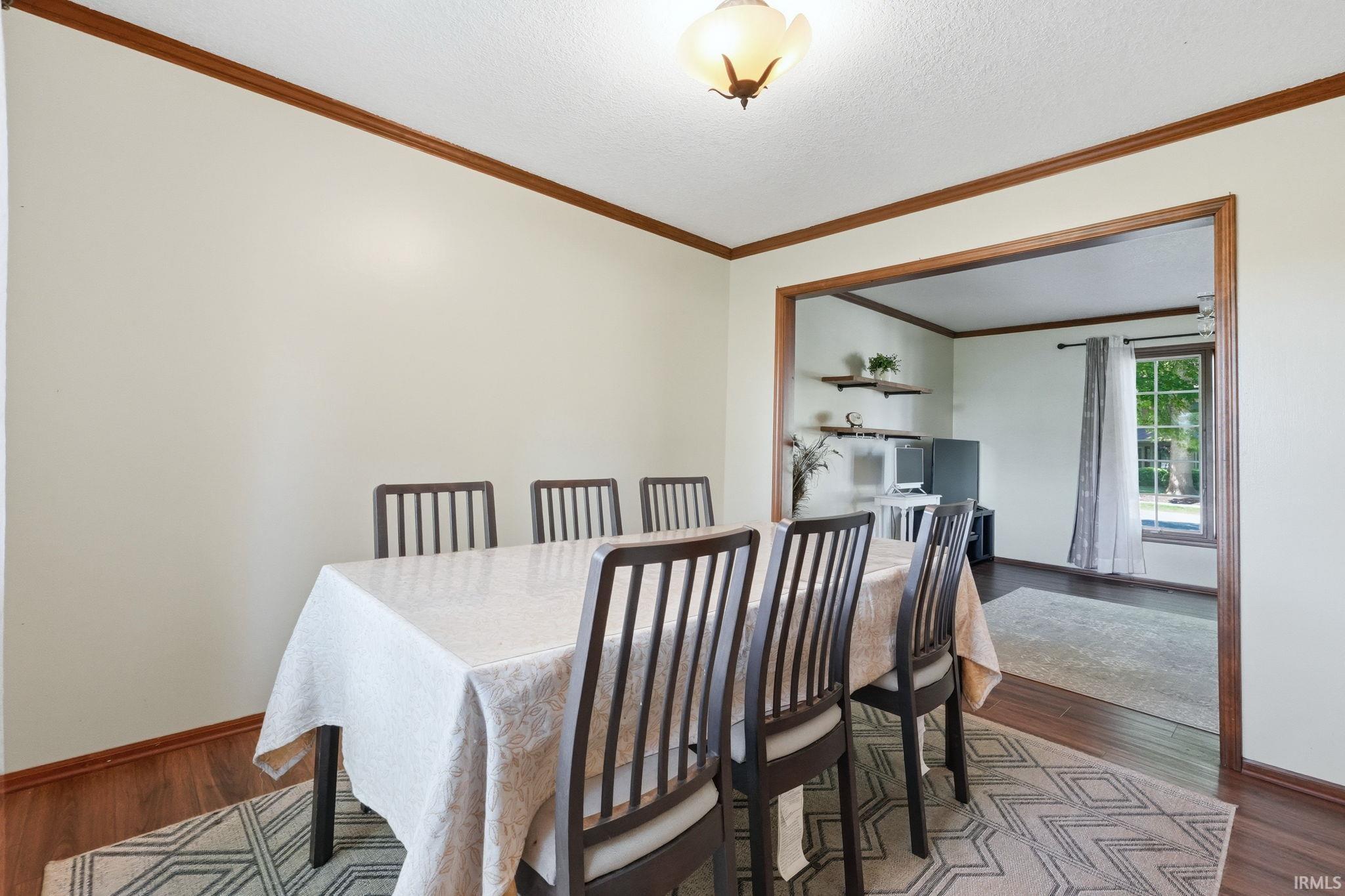 Dining area featuring wood-finish flooring, a decorative overhead light fixture, and wood trim detailing