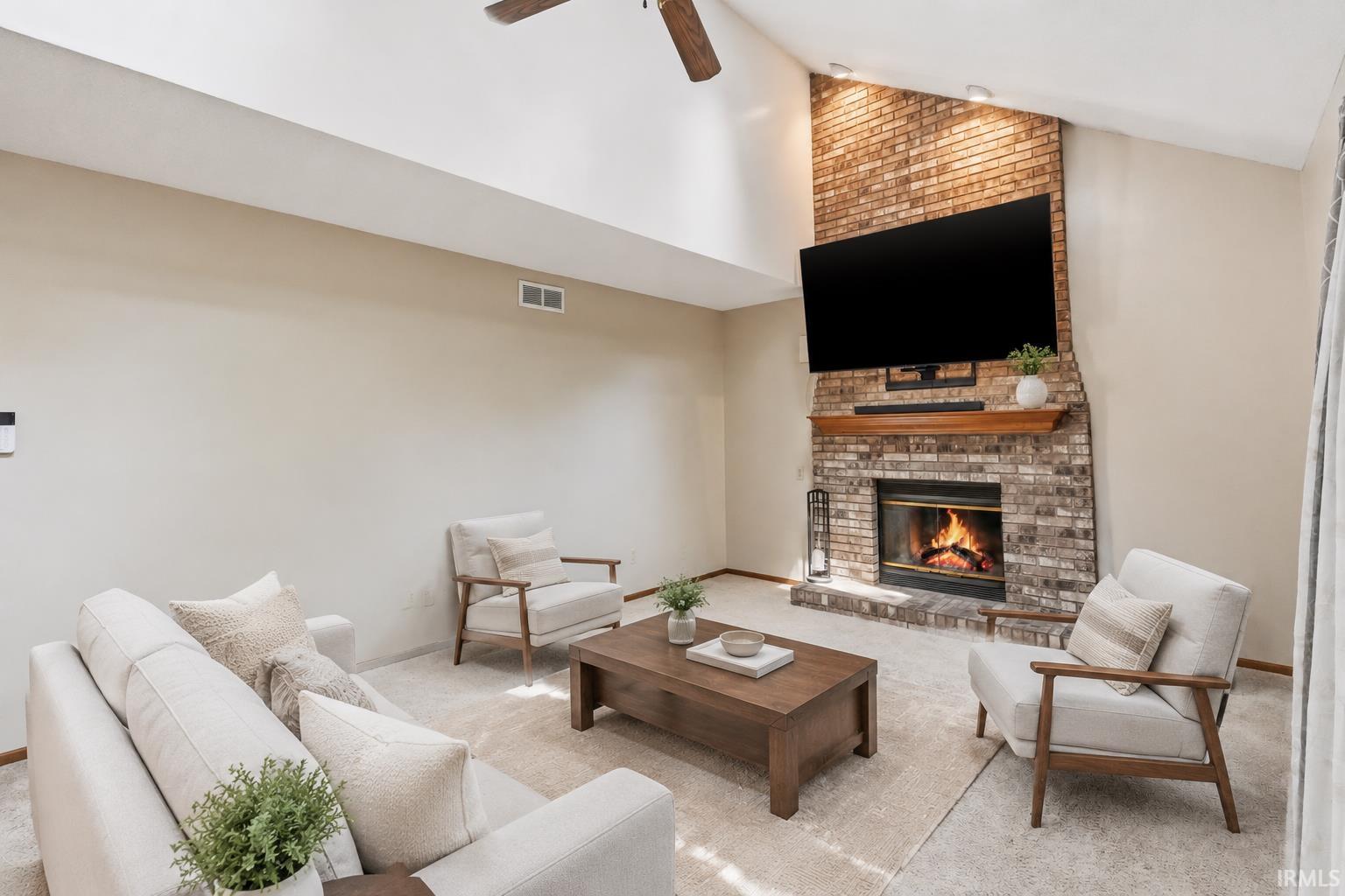 Brick-surround fireplace with a wood mantle, vaulted ceiling, and a ceiling fan