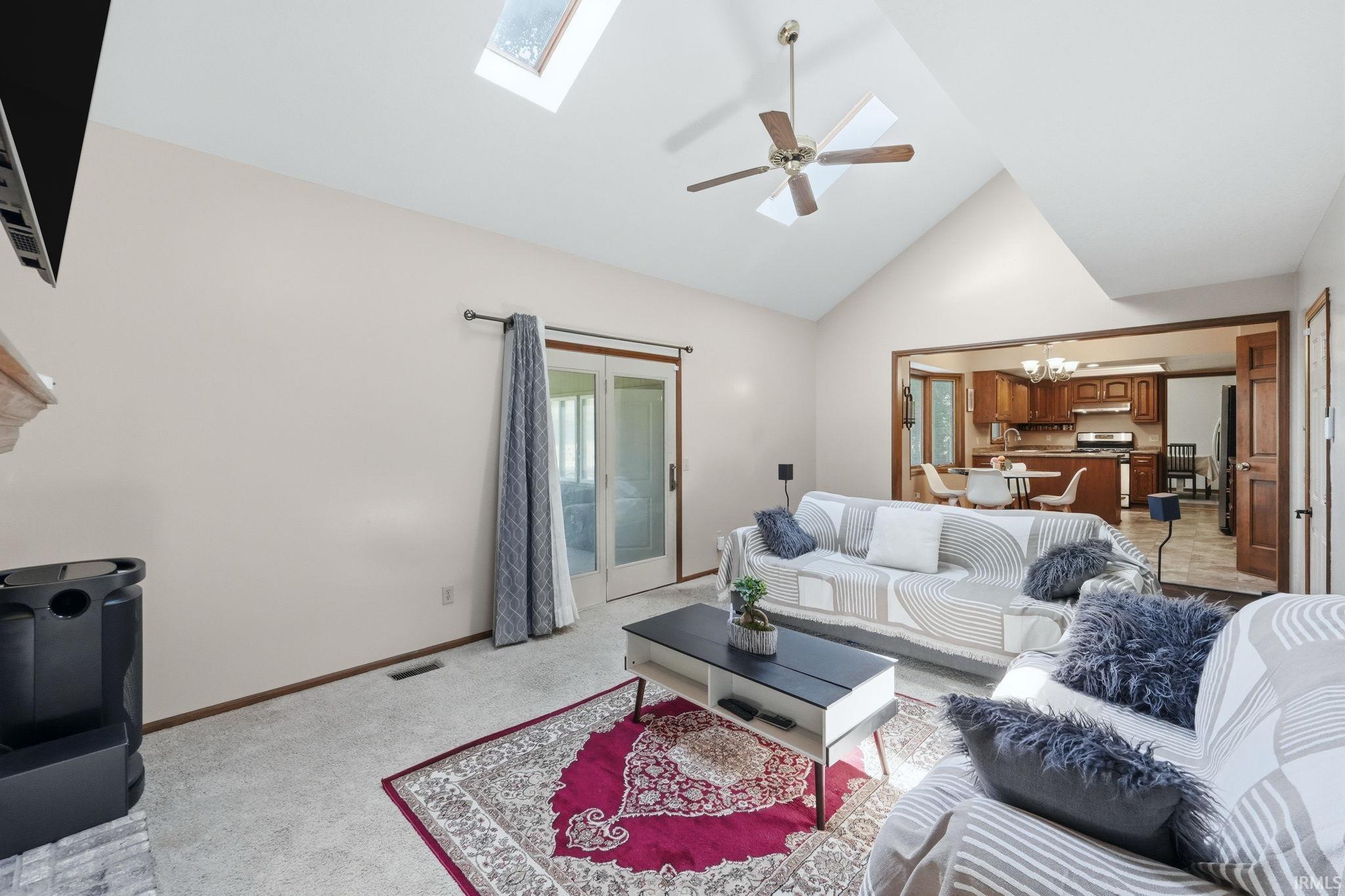 Vaulted ceiling living room featuring a ceiling fan, recessed skylights, and a glass sliding door