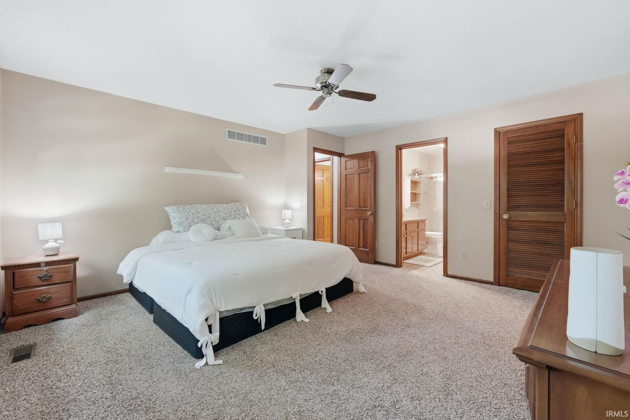 Carpeted room featuring a ceiling fan, light-toned walls, and wood-paneled doors