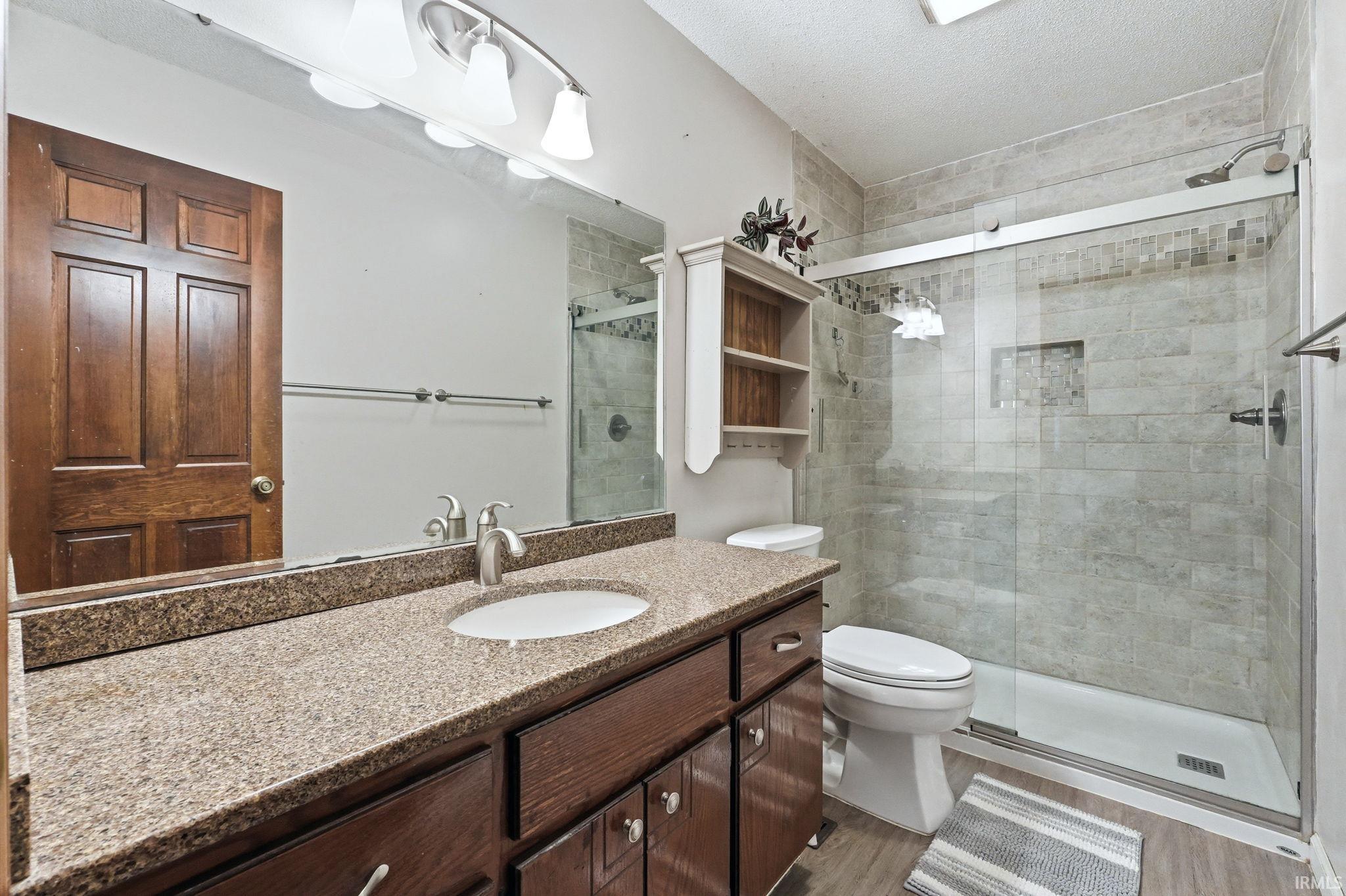 Bathroom featuring a vanity with a granite-finish countertop, undermount sink, and wood-finish cabinetry