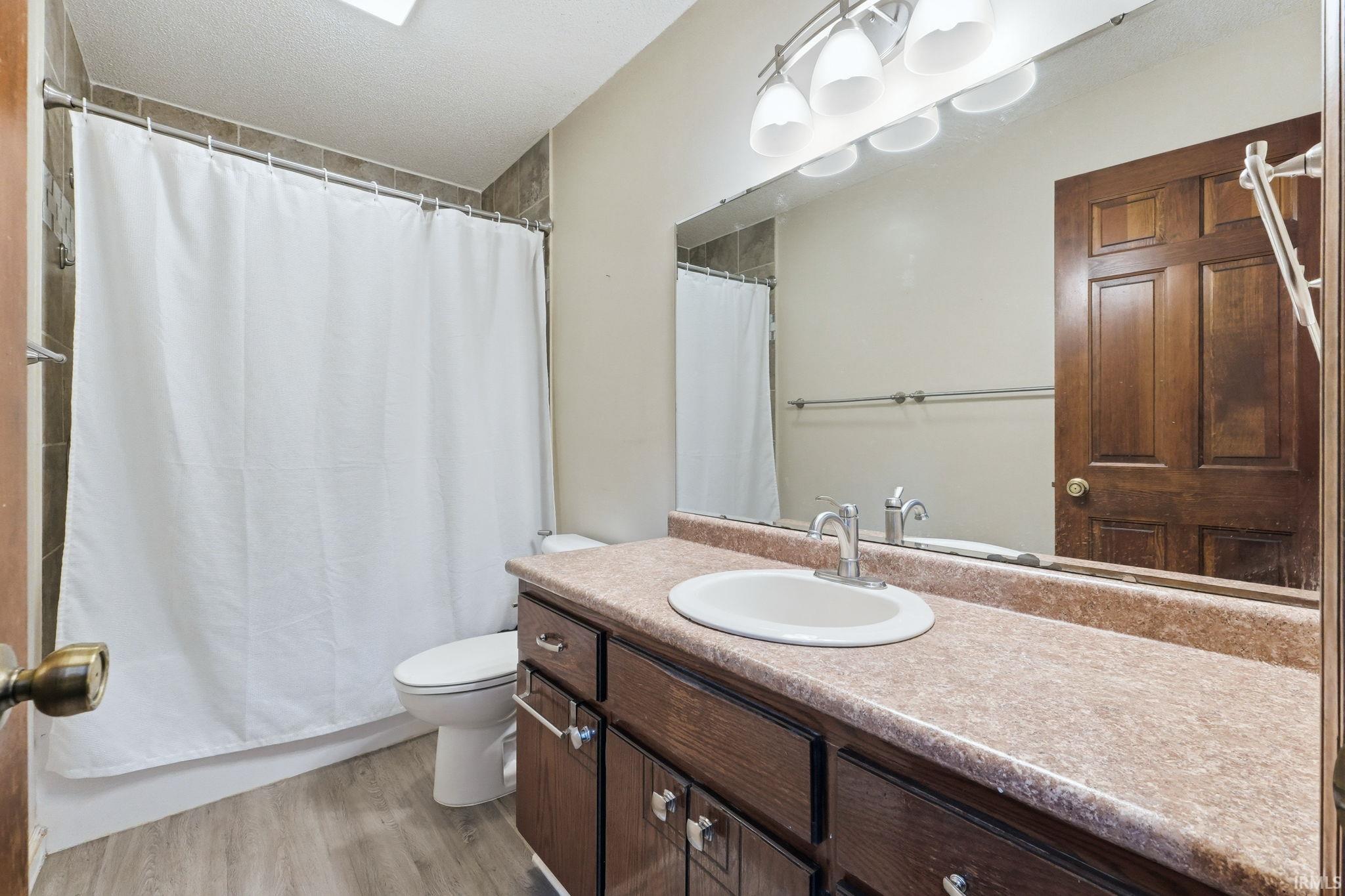 Bathroom vanity with a composite countertop, undermount sink, and wood-finish cabinetry