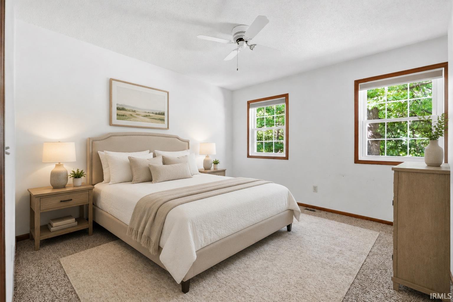 White walls with two paneled windows featuring wood trim, ceiling fan light fixture, and textured carpet flooring