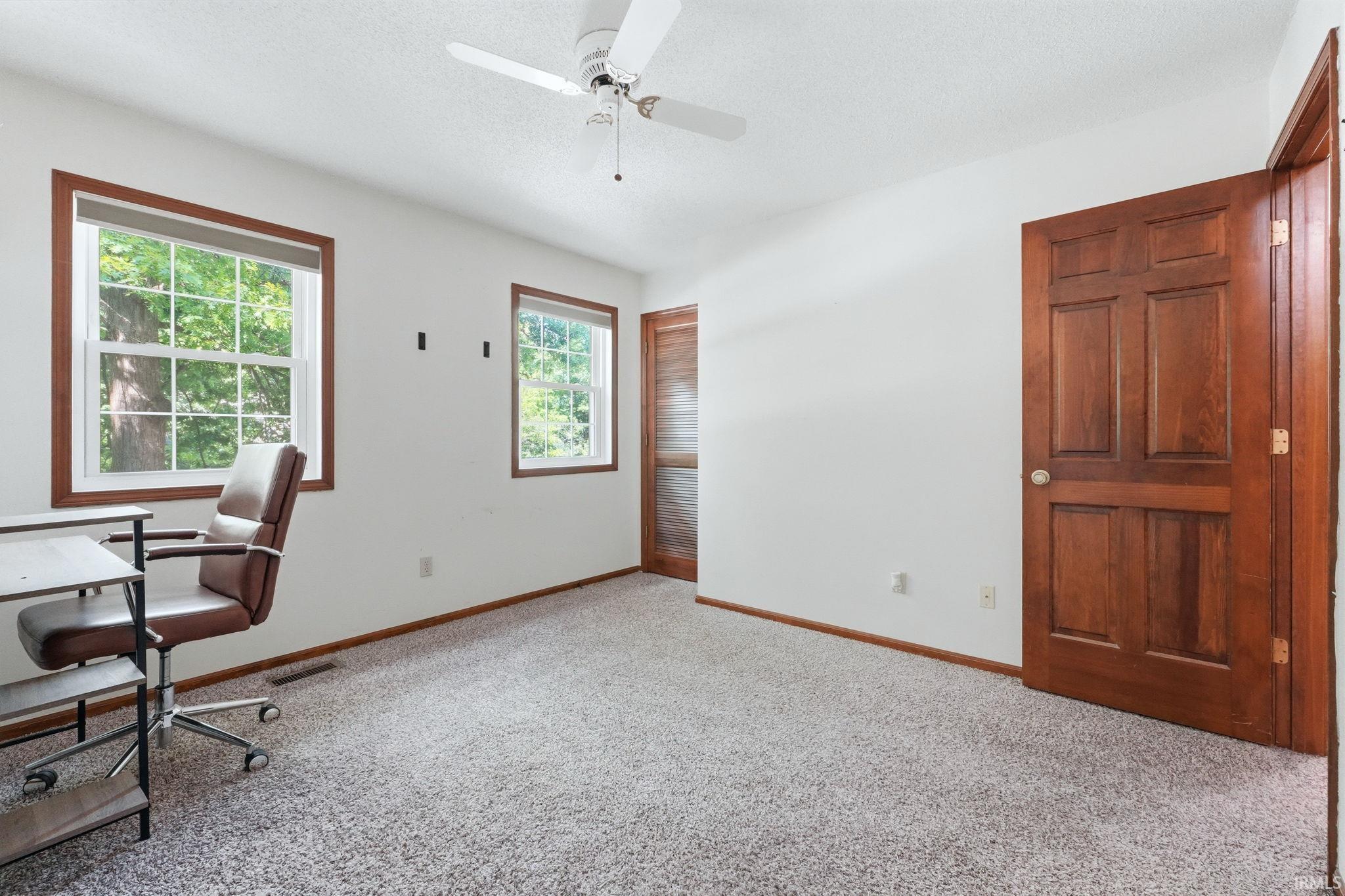 Bright interior space with light gray flecked carpet, white walls, and wood trim