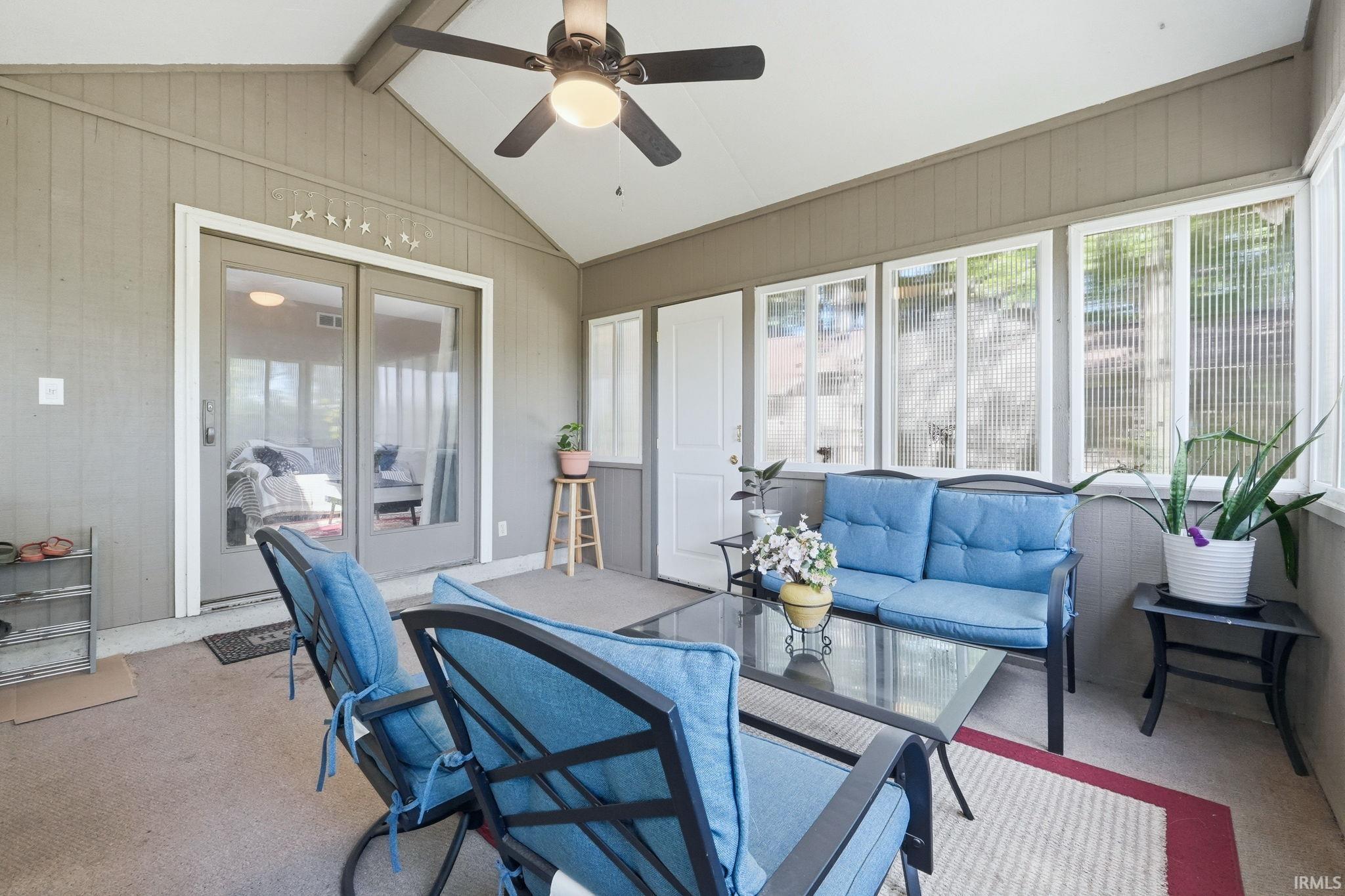 Screened-in porch featuring a vaulted ceiling and a ceiling fan