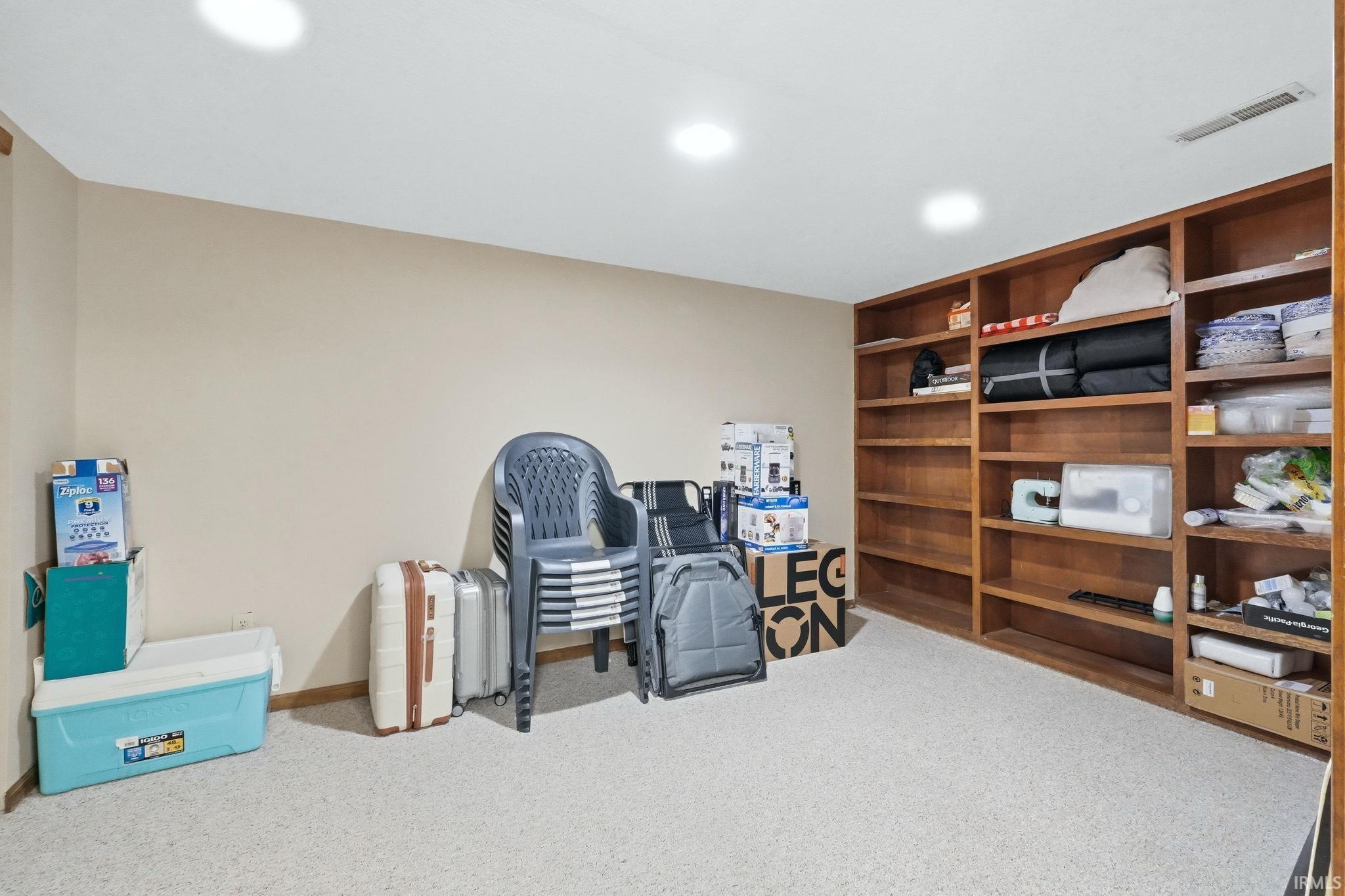 Recessed lighting illuminates this room, featuring light-toned wall paint and textured carpeting