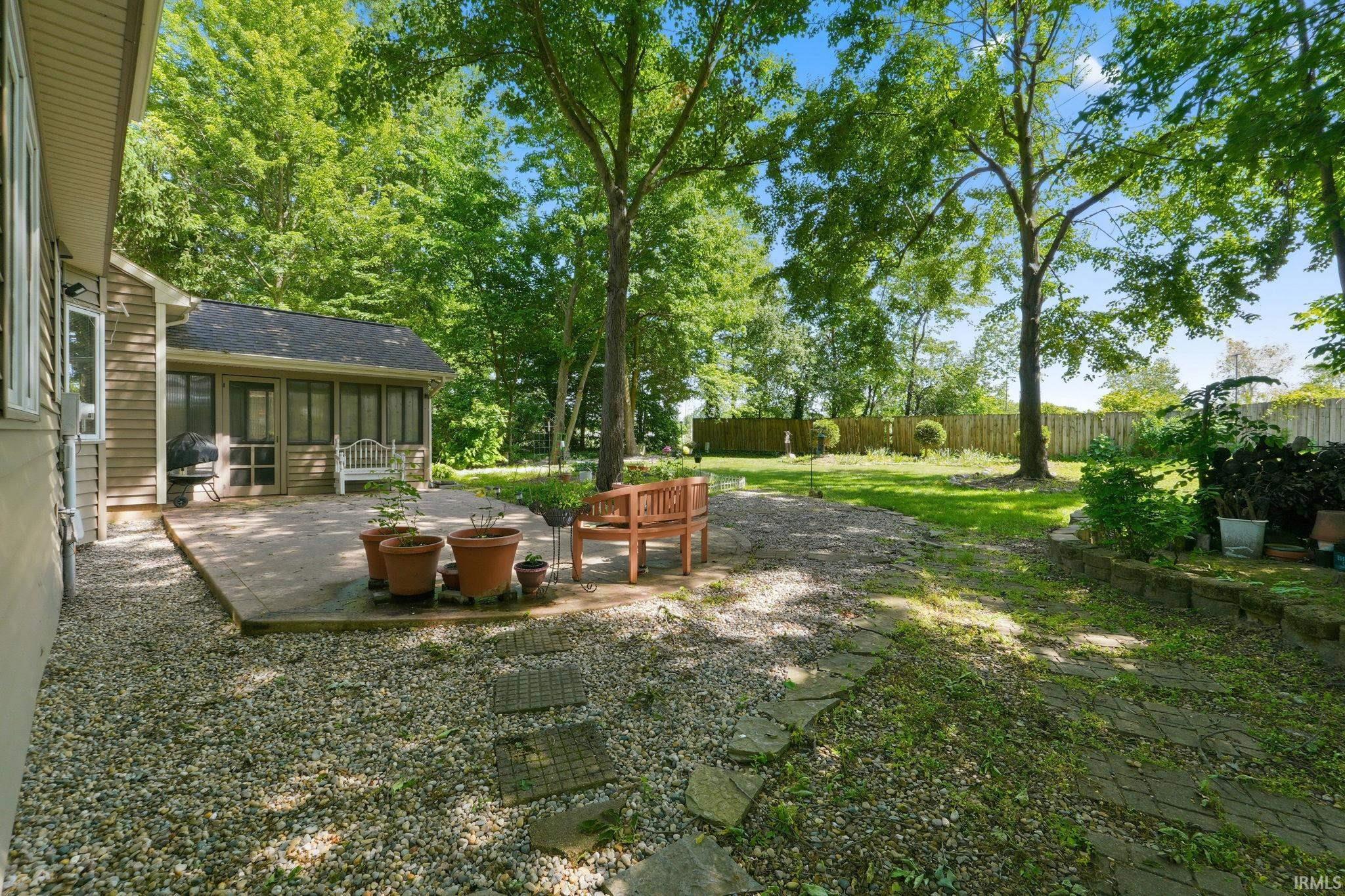 Expansive backyard featuring a screened-in porch, paver patio, and mature trees