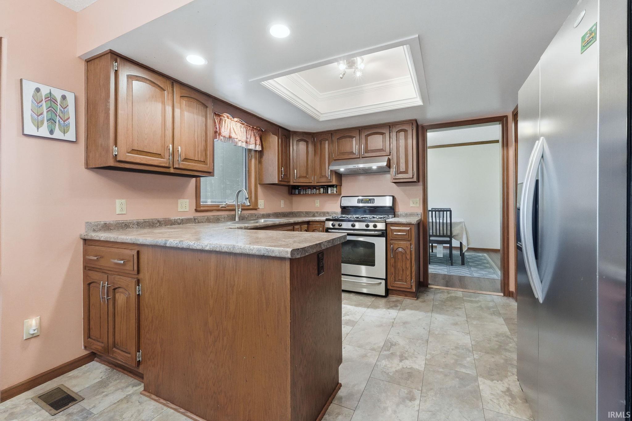 Kitchen featuring wood-finish cabinetry, stainless steel appliances, a recessed ceiling light fixture, and a skylight