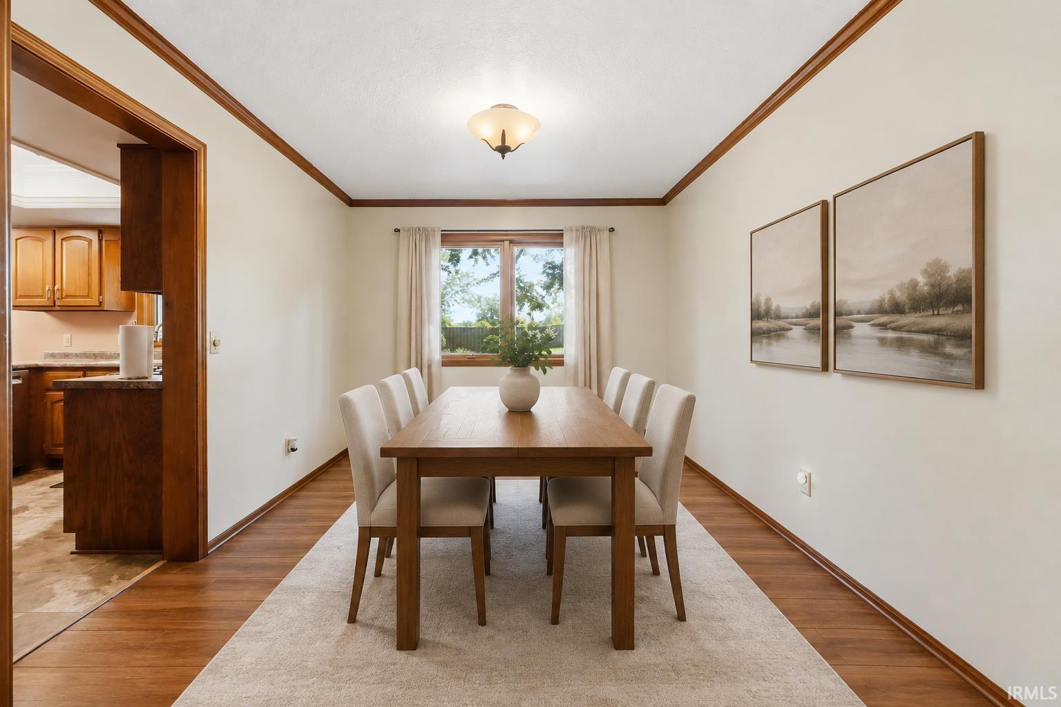 Wood-finish flooring with a neutral wall color, crown molding, and a flush mount light fixture