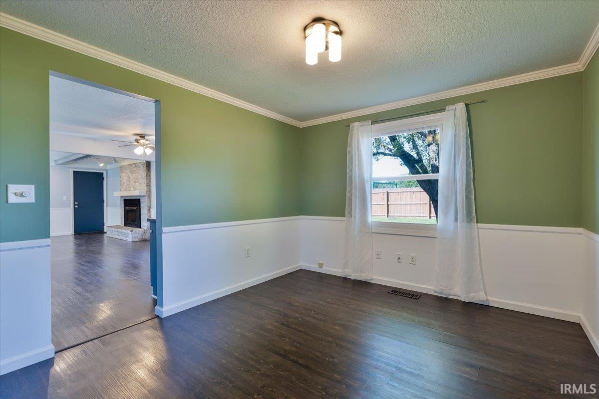 Room featuring dark wood-finish flooring, two-tone walls with white wainscoting, and a window offering natural light