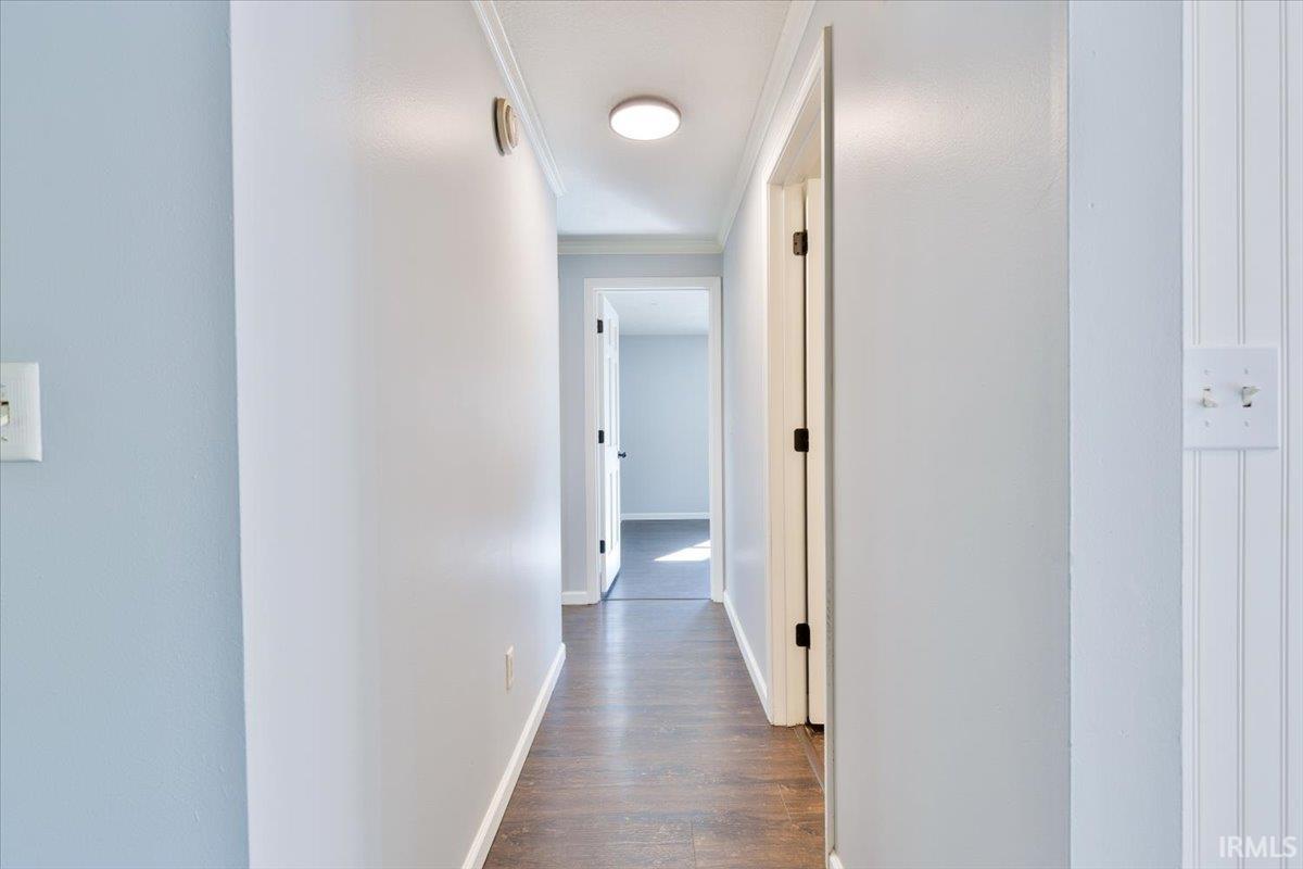 Hallway featuring wood-finish flooring, light blue wall paint, white trim, and a ceiling-mounted light fixture