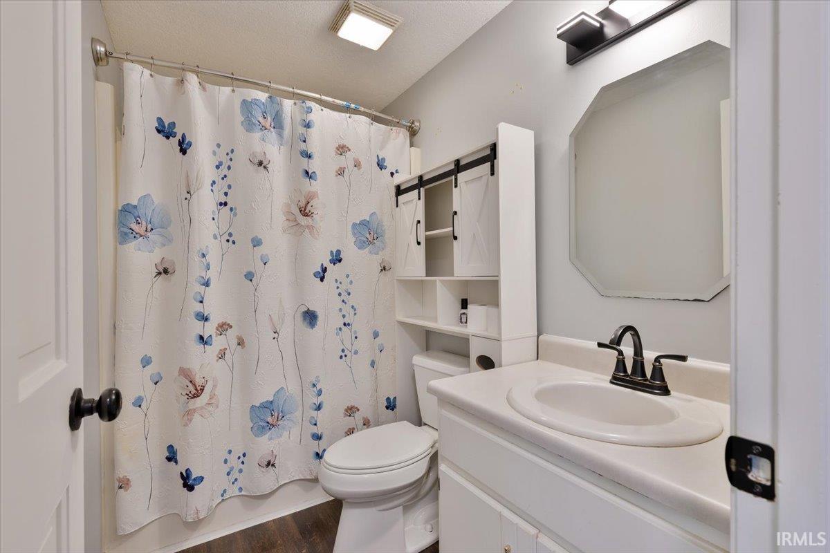 Bathroom featuring a white vanity with integrated sink, black-finish faucet, and an octagonal wall mirror