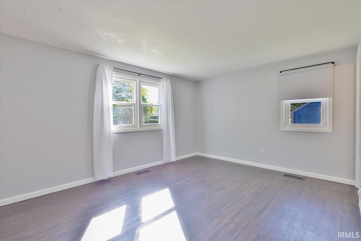 Spacious room featuring wood-finish flooring, light grey walls, and white trim