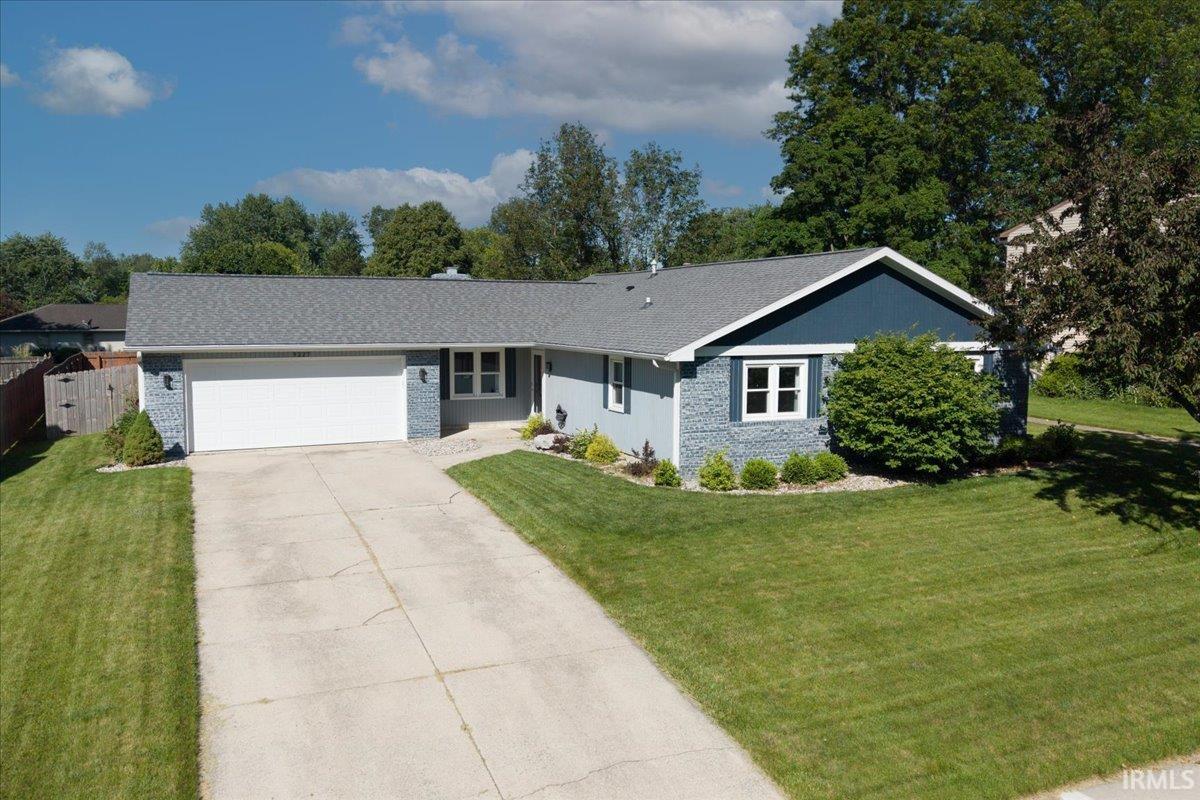 Ranch-style residence featuring a prominent two-car garage, concrete driveway, and front landscaping