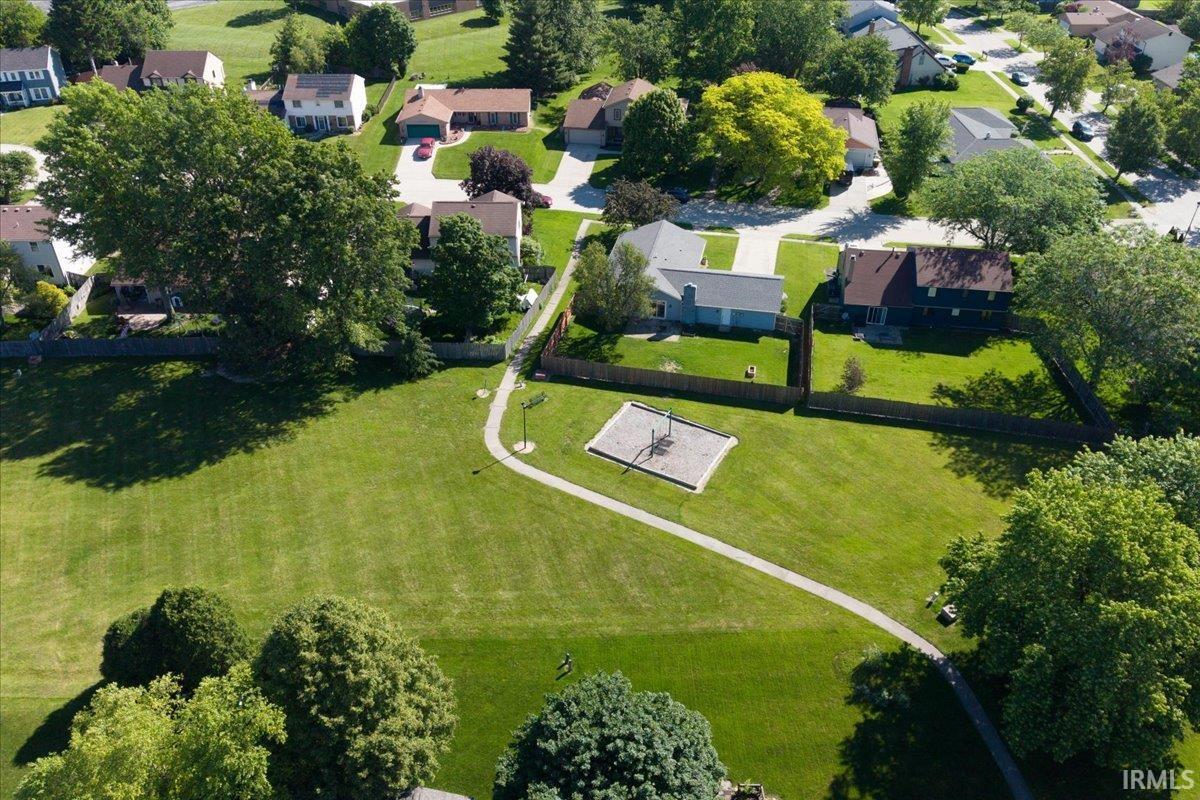 Expansive property featuring a manicured lawn, mature trees, and a direct access point to a community park with a playground
