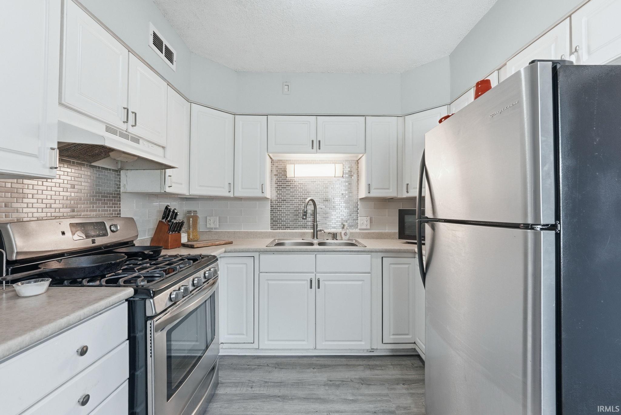 Kitchen featuring white cabinetry, light-toned countertops, and stainless steel appliances