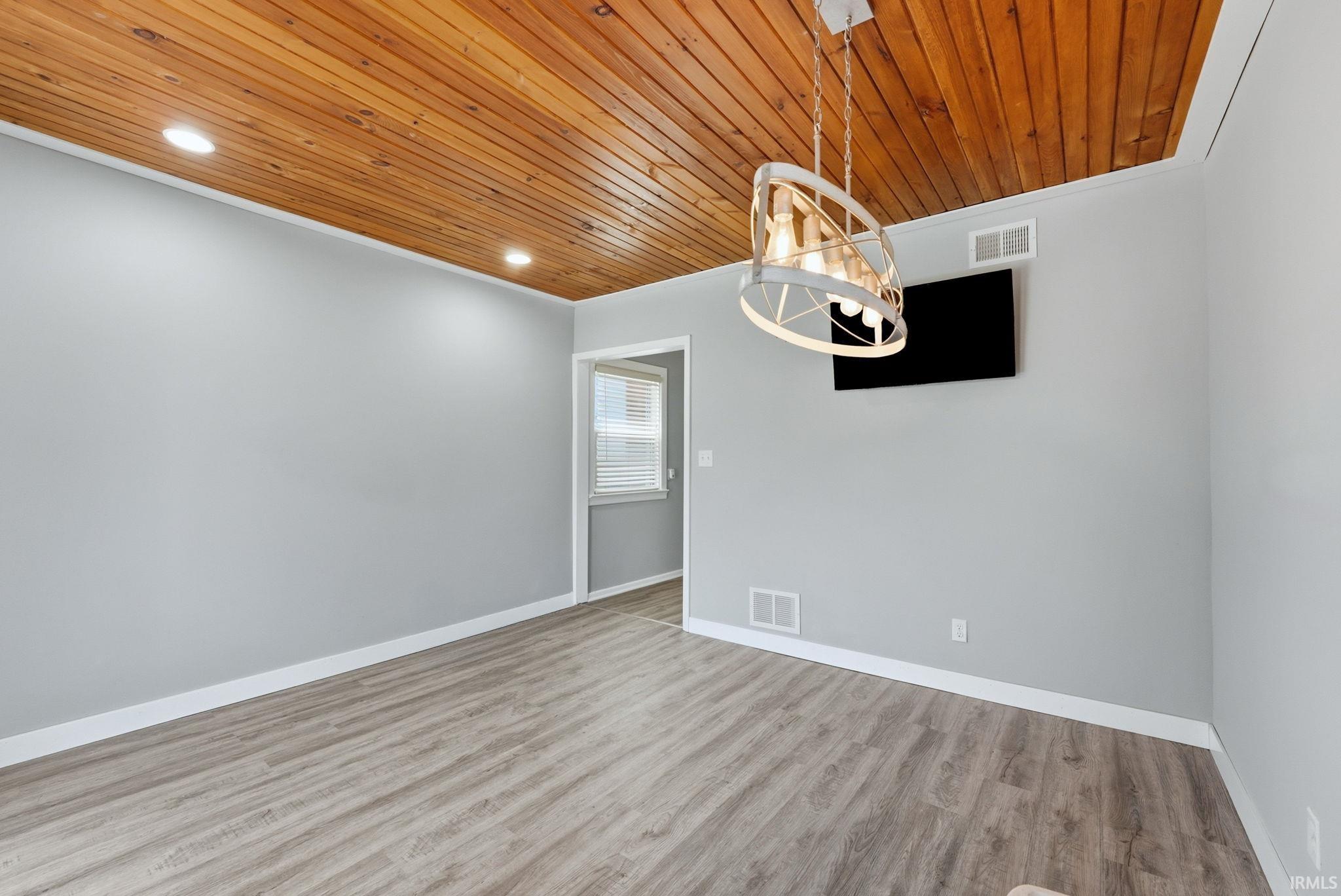 Room featuring a wood-panel ceiling, recessed lighting, and a modern chandelier