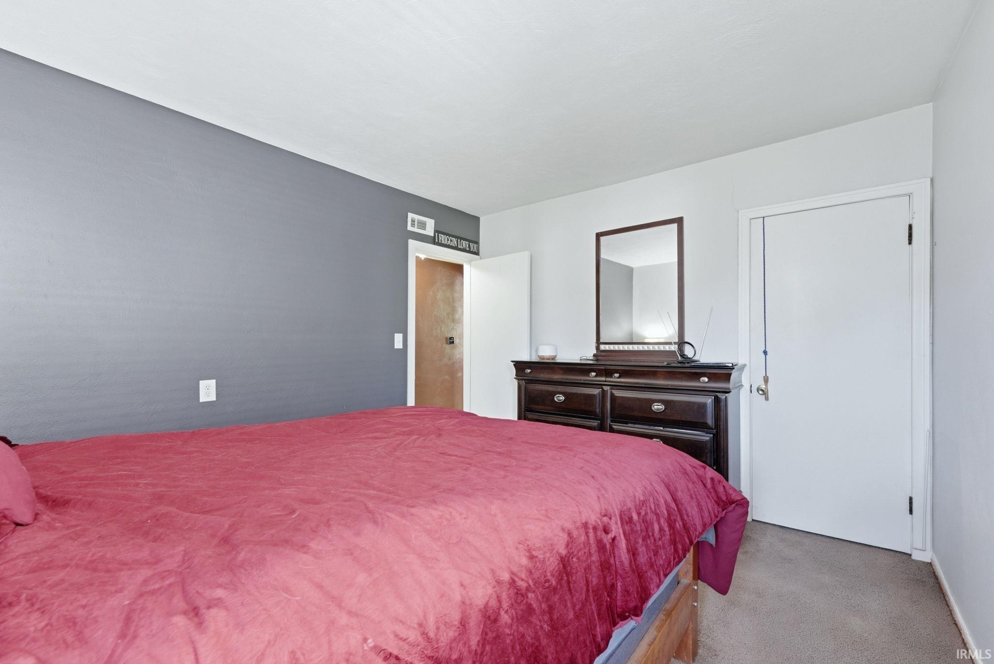 Carpeted room featuring a neutral color palette with a prominent accent wall