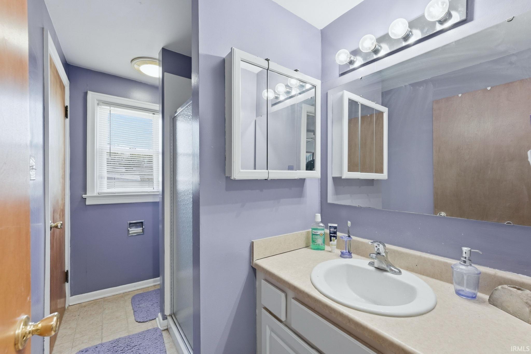 Bathroom featuring a vanity with an integrated sink, a large wall-mounted mirror, overhead lighting, and a medicine cabinet