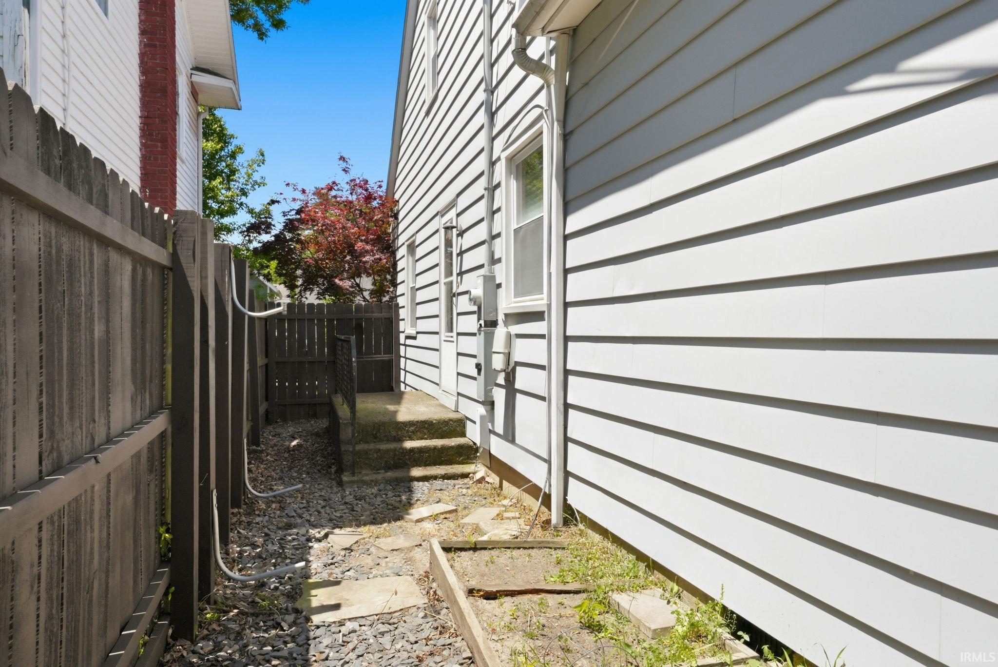 Exterior siding with a window, a white door, and concrete steps