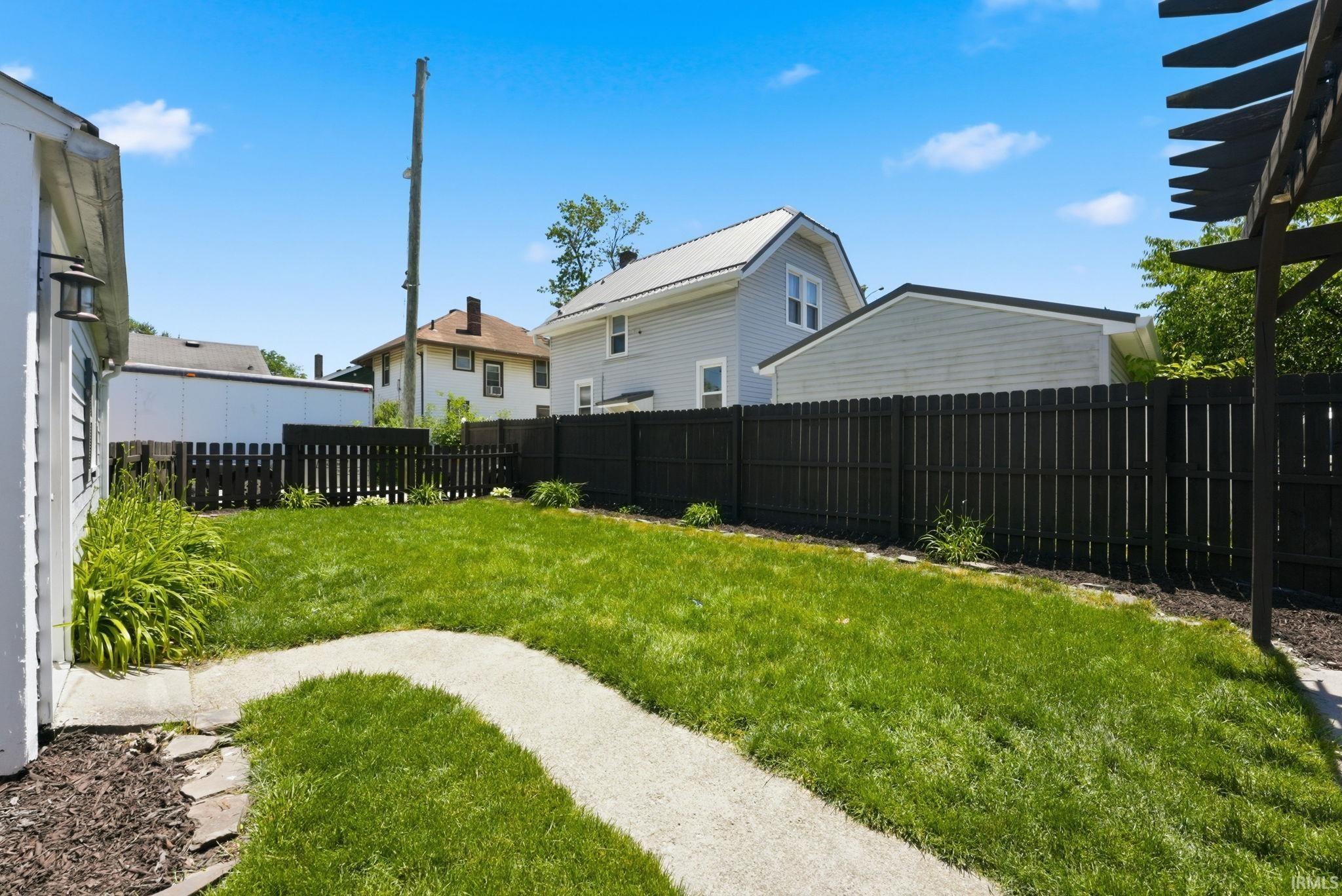 Manicured lawn with a winding aggregate pathway, bordered by a dark picket fence