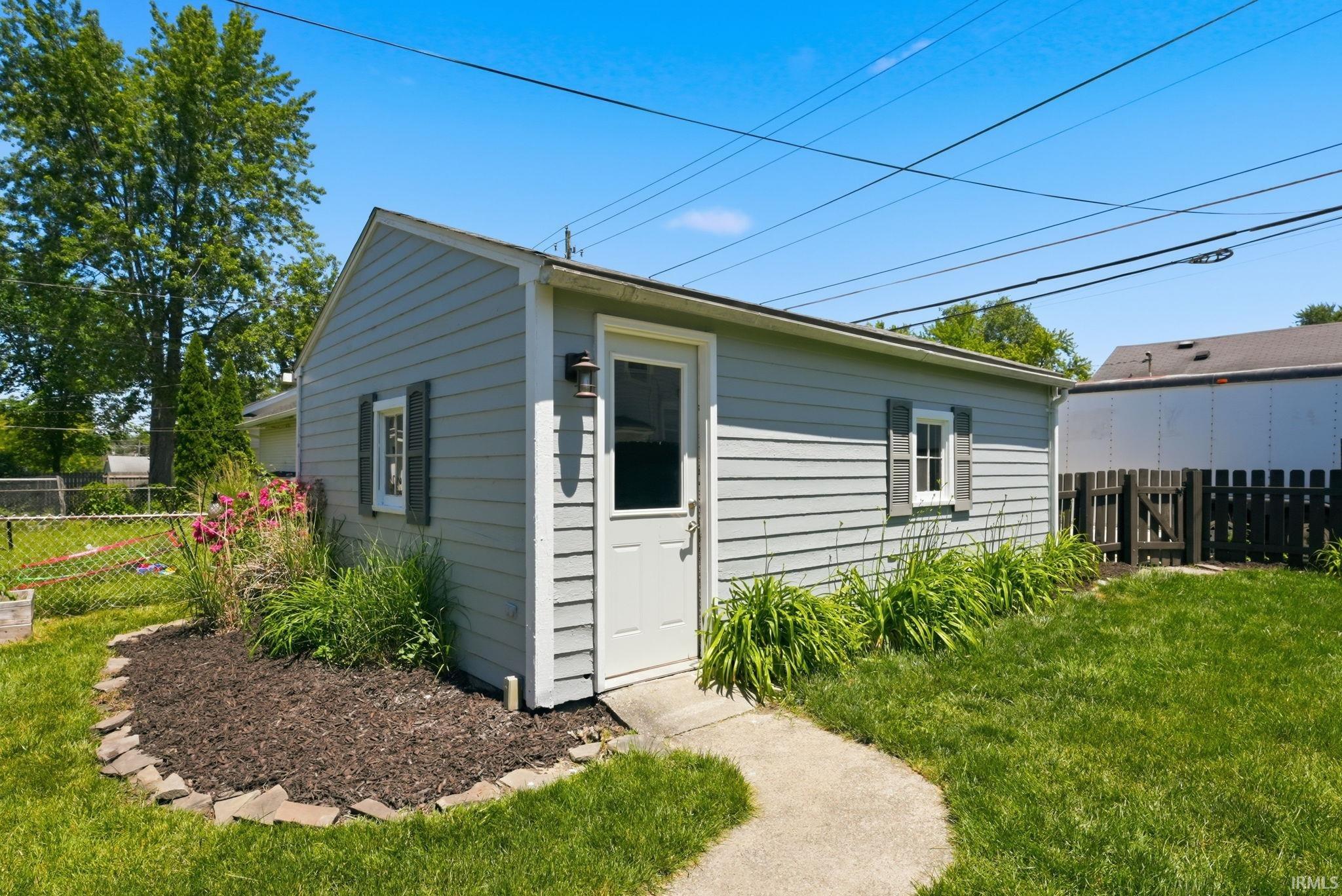 Detached structure featuring light gray horizontal siding and a white entry door
