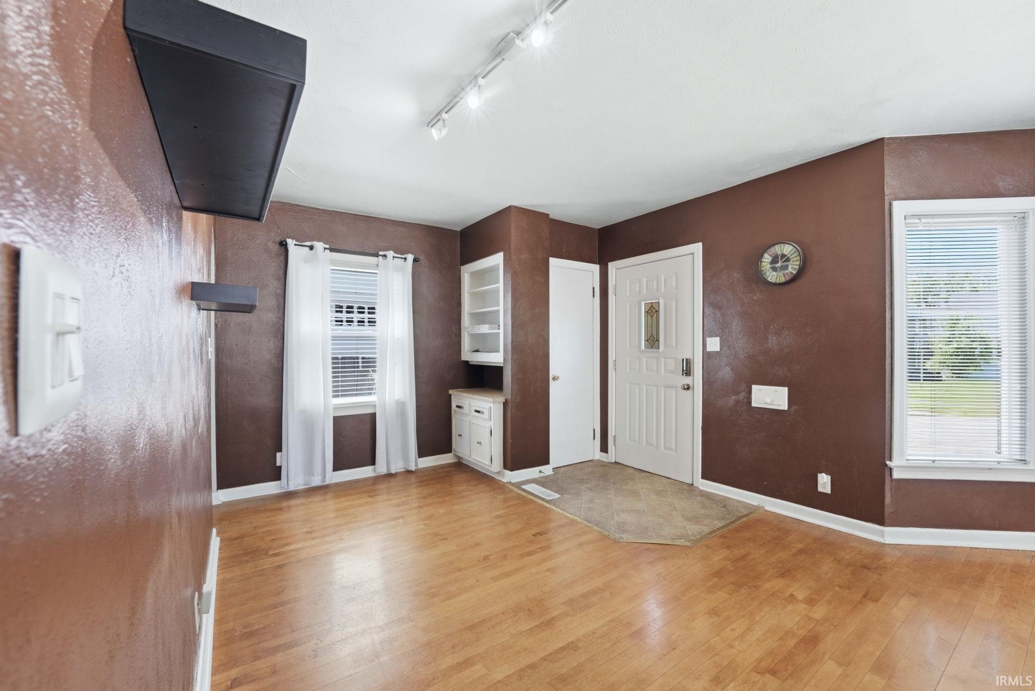 Light wood-finish flooring with track lighting and multiple windows