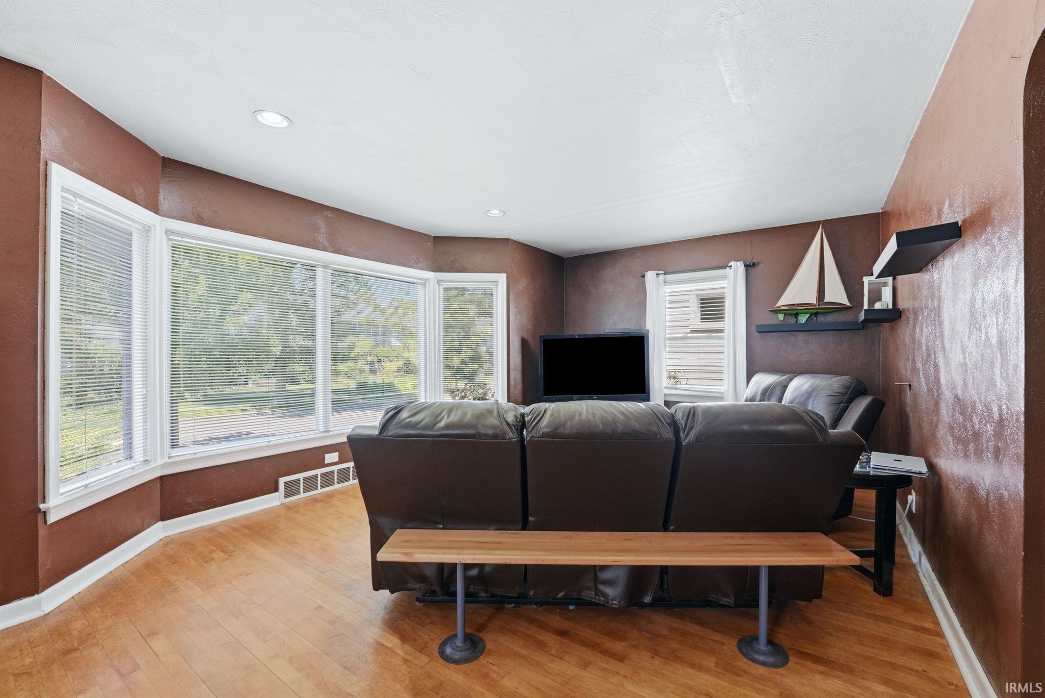 Bay window featuring multiple large windows, recessed lighting, wood-finish flooring, and a wall-mounted shelving unit